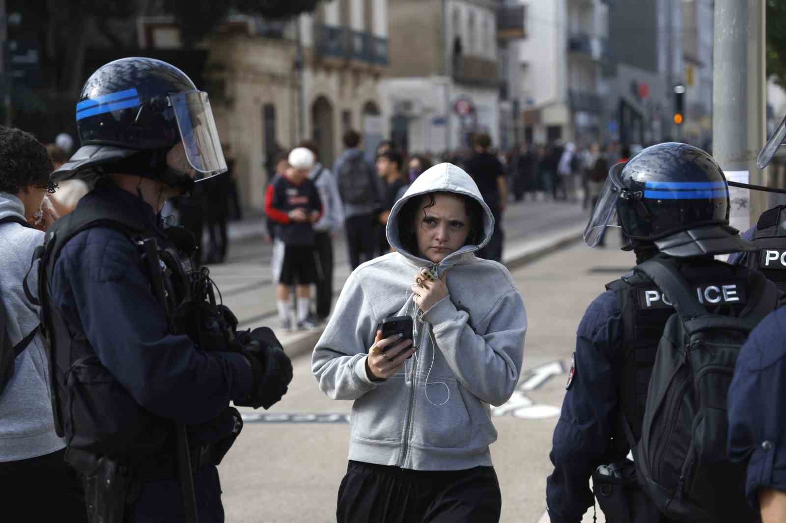 Çevik kuvvet polislerinin bulunduğu bir sokakta genç bir kişi görülüyor.