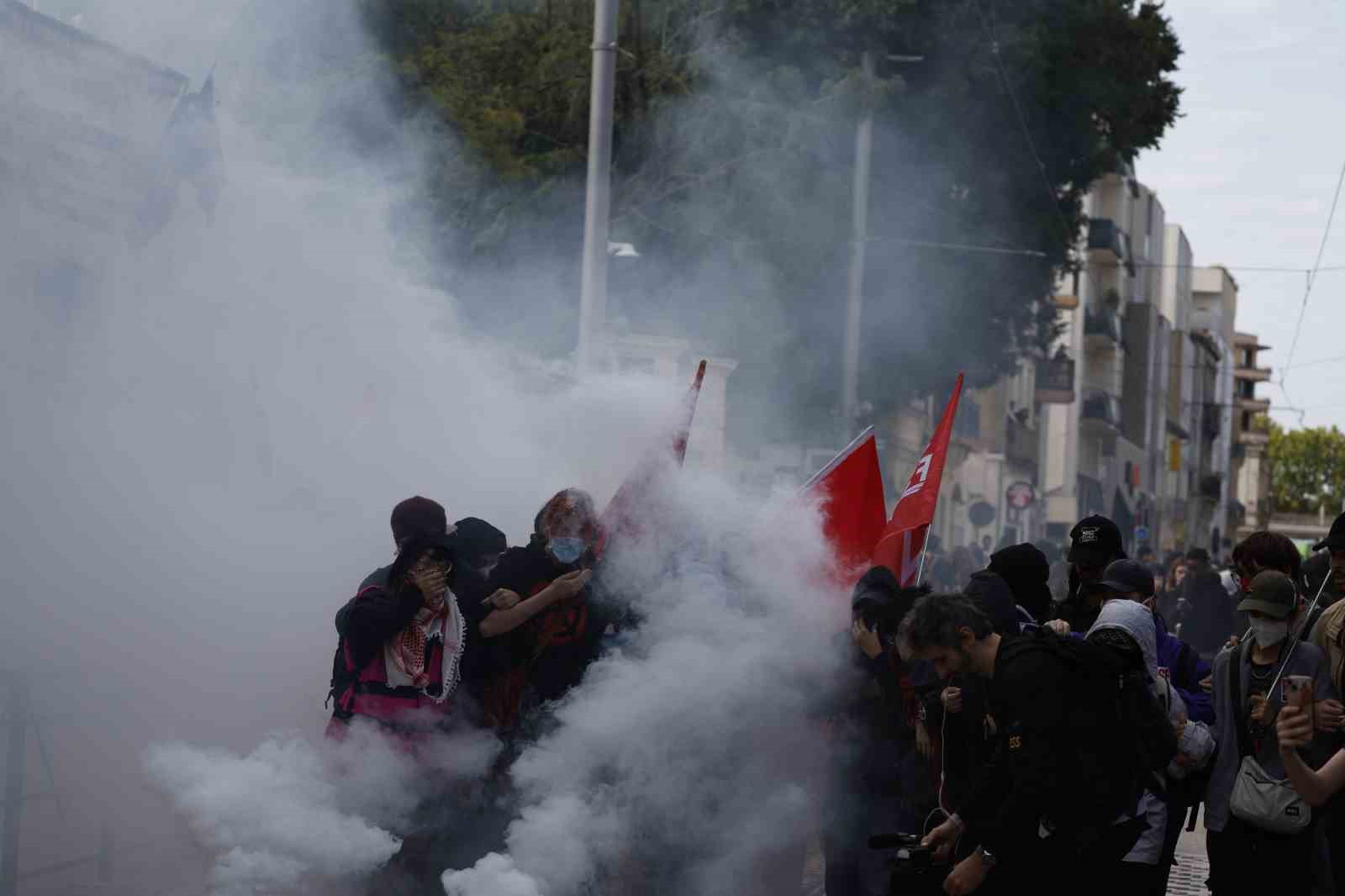 Yoğun duman altında kalan protestocuların bulunduğu bir cadde görülüyor.