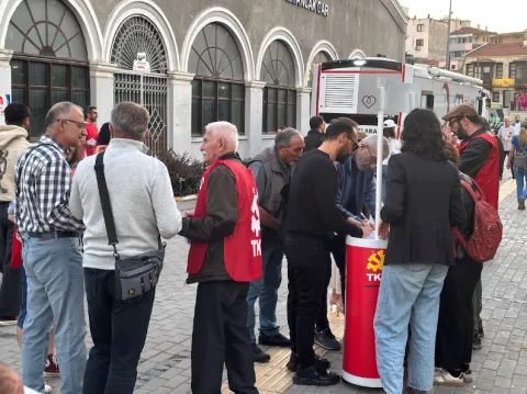 İzmir’de bir meydanda kurulan TKP imza masası çevresinde yurttaşlar ve görevliler.