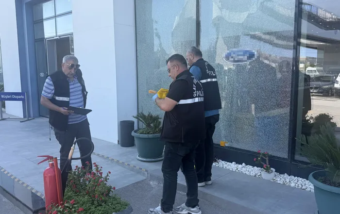 Polis ekiplerinin oto galerinin hasar gören camı önünde yaptığı inceleme.