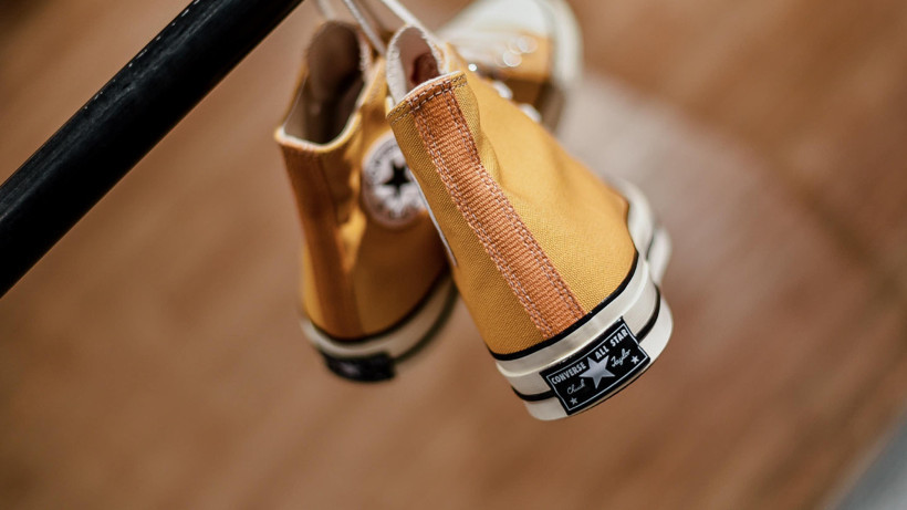 Yellow Converse-style high-top shoes hanging on a rack.