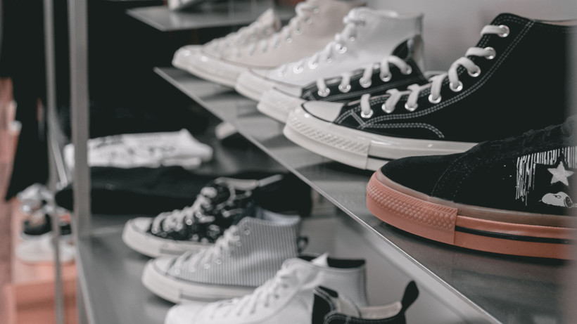 Black and white Converse shoes lined up on shelves.