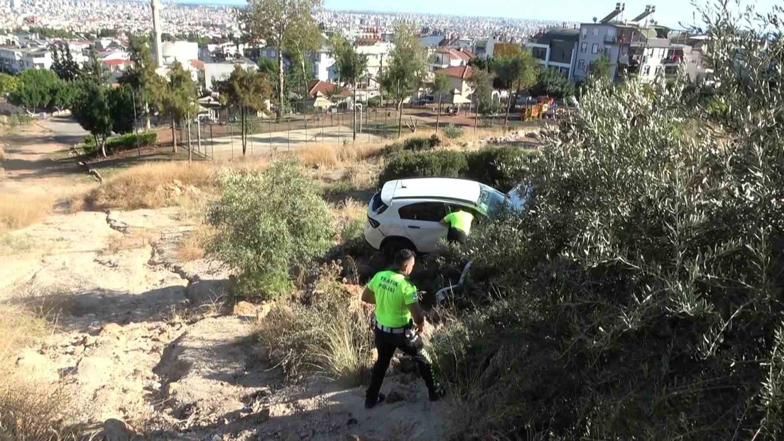 View of traffic police officers next to the white car stuck among the bushes on the slope.