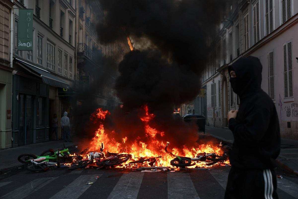 A protest area in a street in France where burning bicycles and thick black smoke are visible.