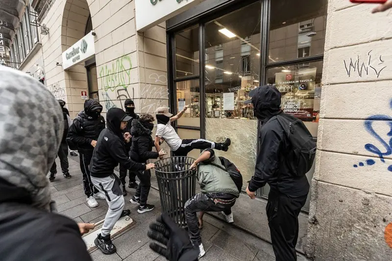 A moment is seen where a masked group damages a shop window in Milan.