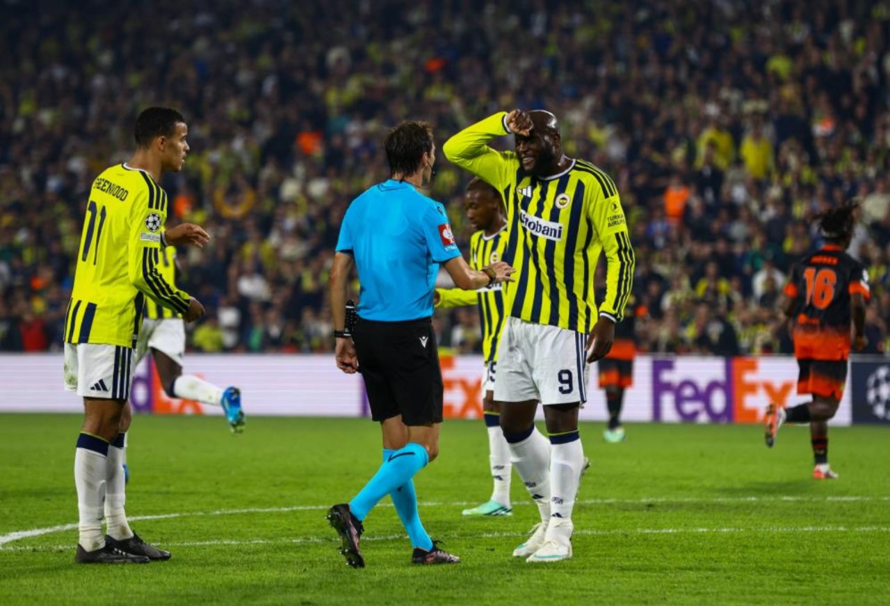 Fenerbahçeli futbolcuların hakemle konuştuğu, arka planda Slavia Prag oyuncularının bulunduğu maç anı.