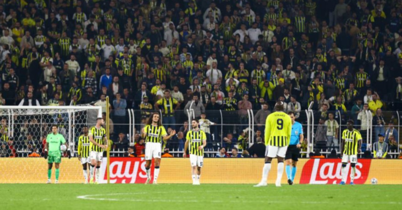 Fenerbahçeli futbolcuların maç sırasında sahada beklediği, tribünlerin arkada görüldüğü kare.