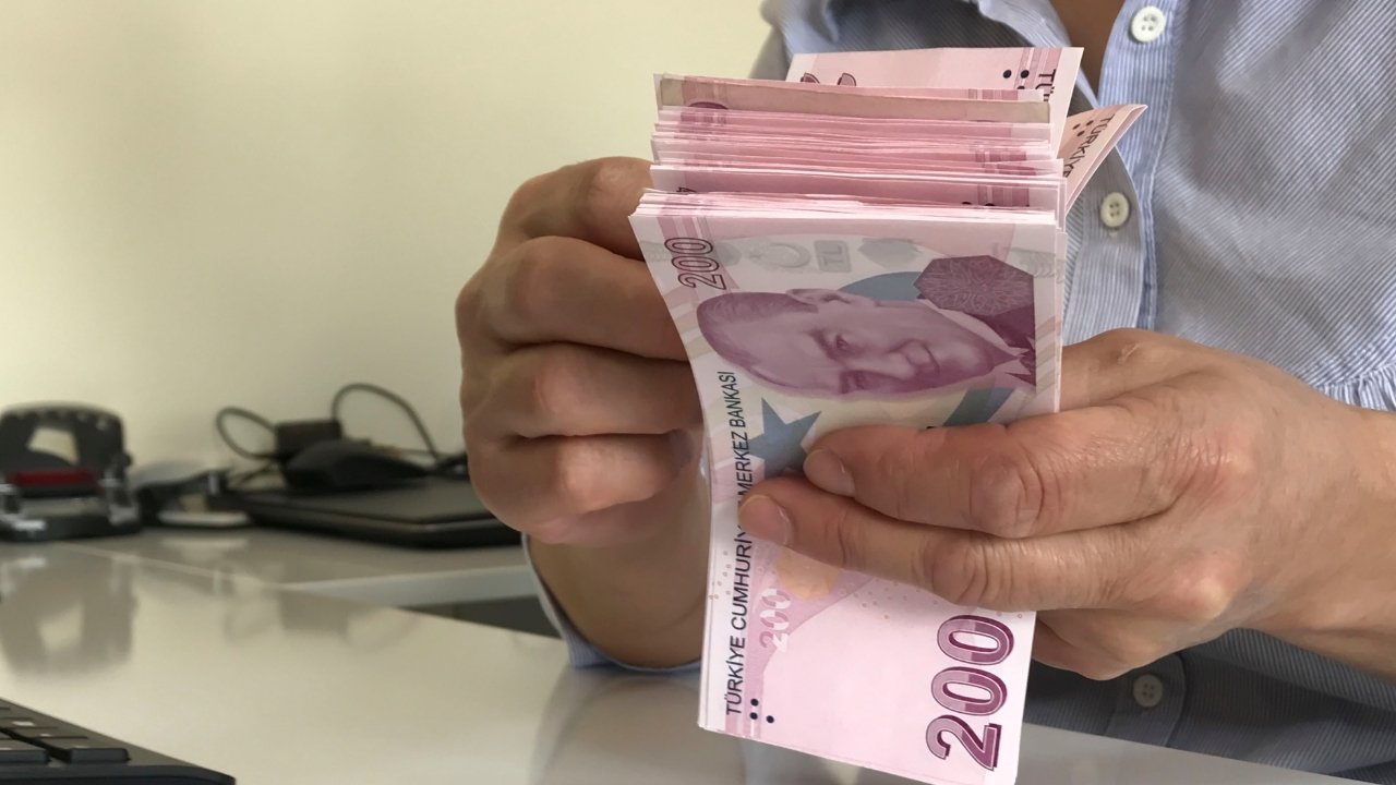 Close-up view of a person counting Turkish lira banknotes in their hand.