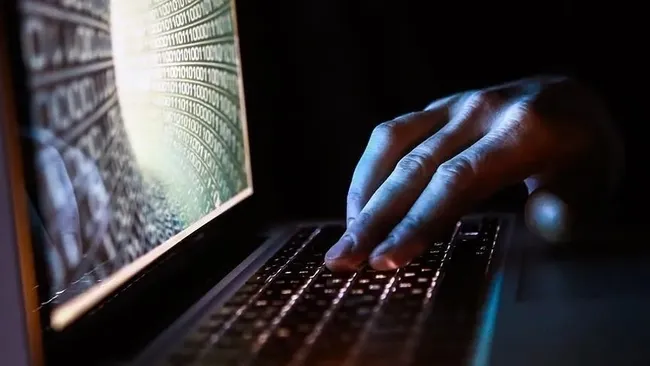 Una persona che lavora su una tastiera di computer e un'immagine di codice digitale sullo schermo.