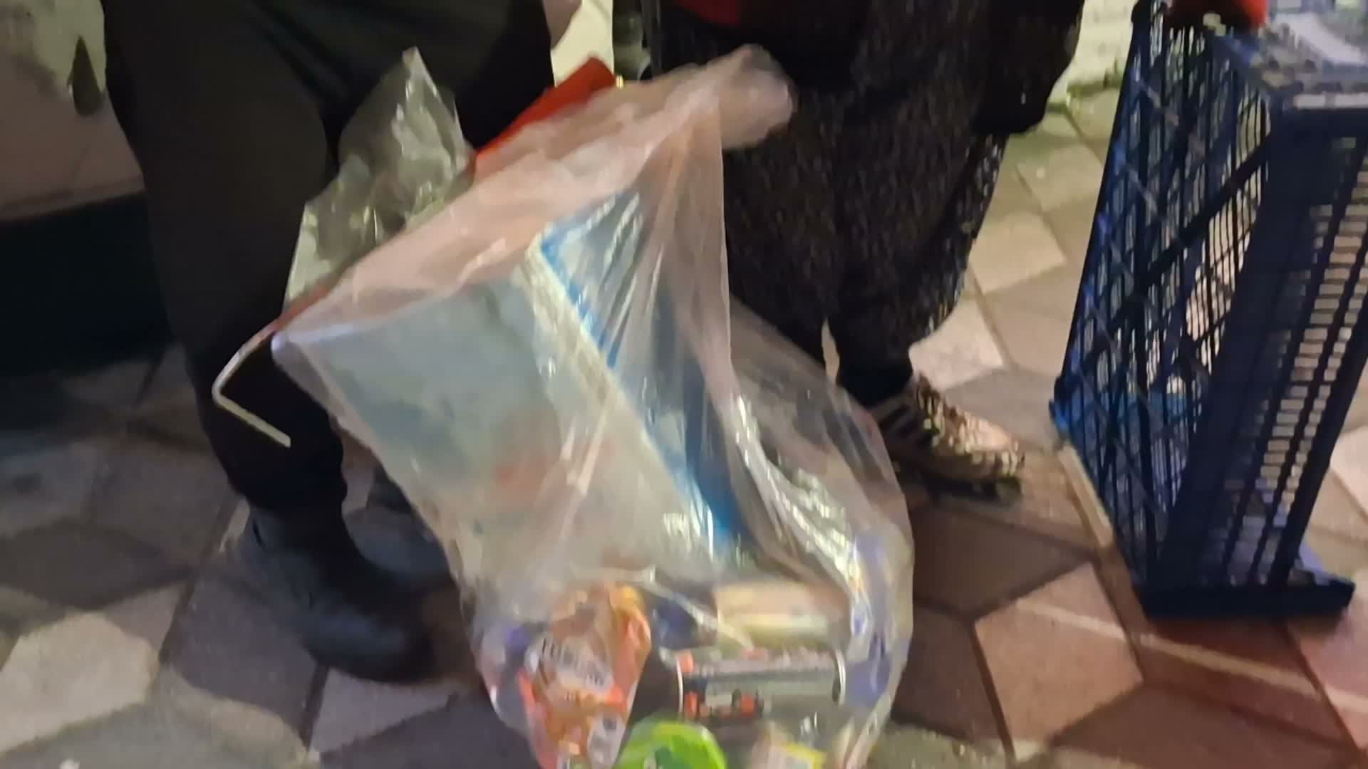 A bag containing cans and waste collected on the street at night.