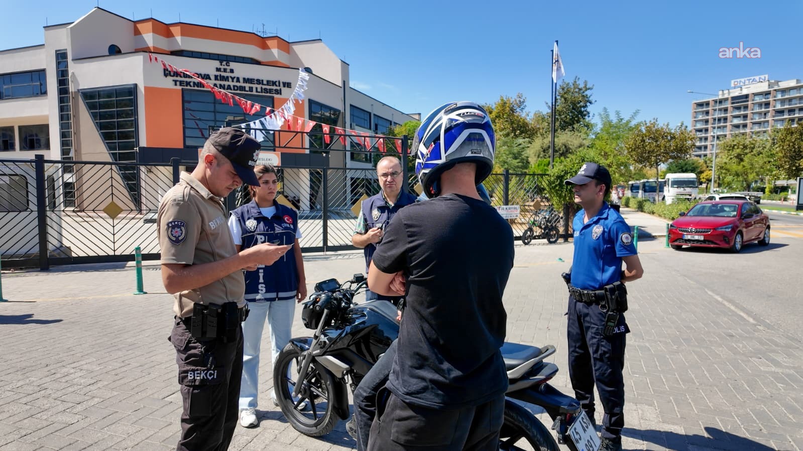 Okul önünde motosiklet sürücüsünü kontrol eden polis ve bekçi ekipleri.