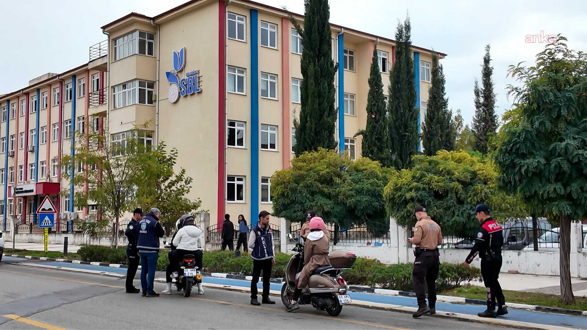 Okul binası önünde polis ve trafik ekiplerinin araç kontrolü yaptığı görüntü.