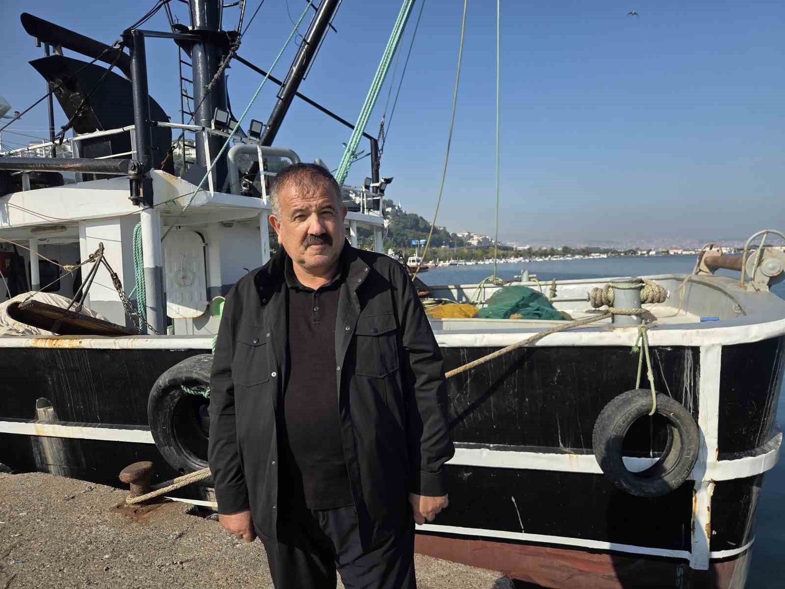 Atıf Malkoç making a statement in front of a fishing boat.