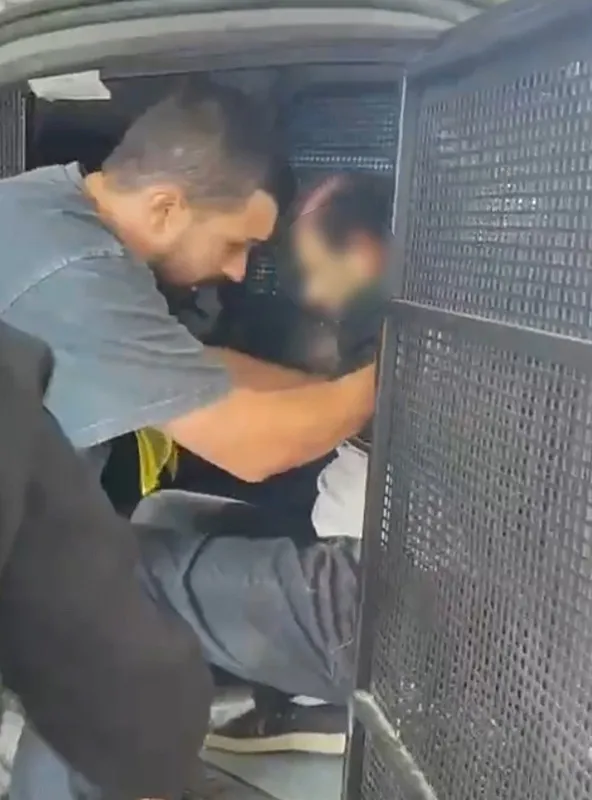 Polis aracında olduğu görülen şüphelinin yüzü bulanıklaştırılmış görüntüsü.