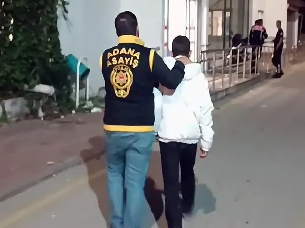 Adana Asayiş ekiplerinden bir polisin gözaltındaki şüpheliyi götürdüğü an.