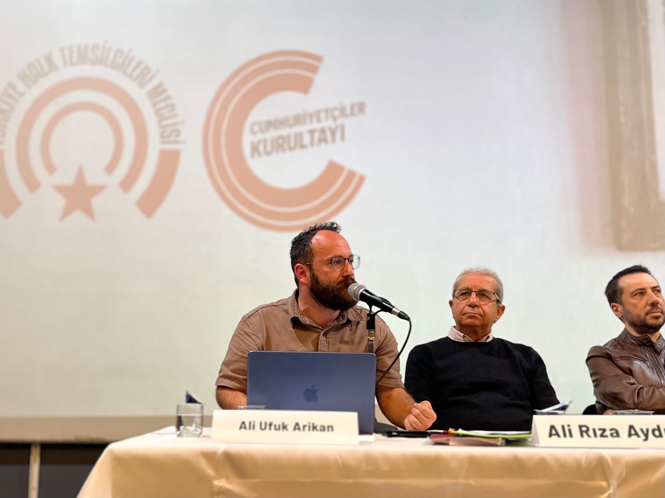 Ali Ufuk Arikan’ın forumda mikrofon başında konuştuğu panel görüntüsü.