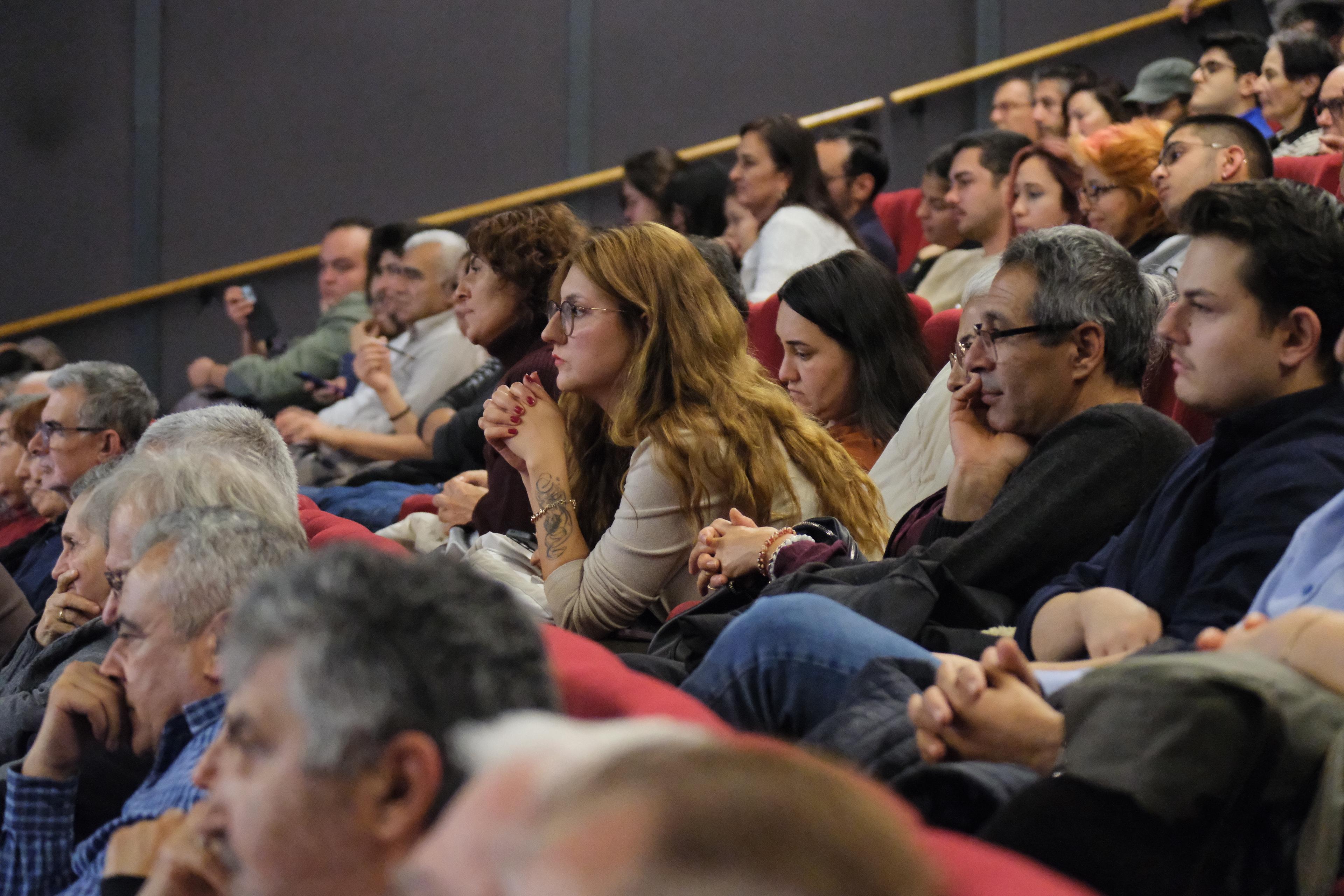 Konferans salonunda forumu izleyen katılımcıların yan açıdan görüntüsü.