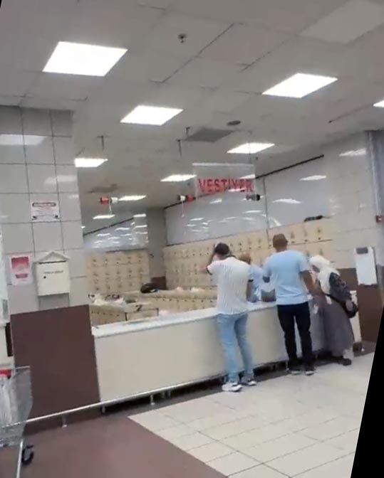 Des clients attendant devant le vestiaire et les casiers verrouillés à l'entrée d'un supermarché.