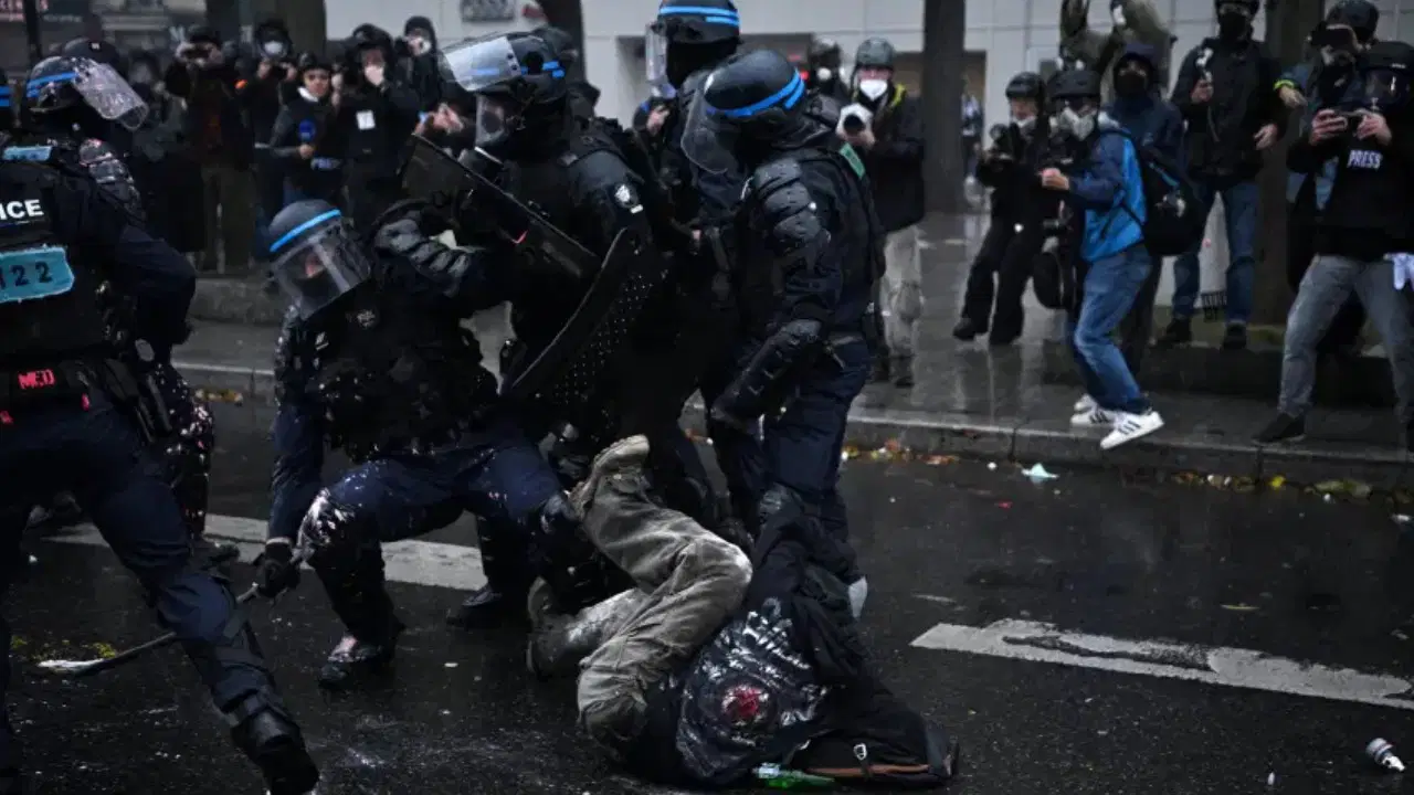 Polis ekiplerinin bir göstericiye müdahale ettiği protesto görüntüsü.