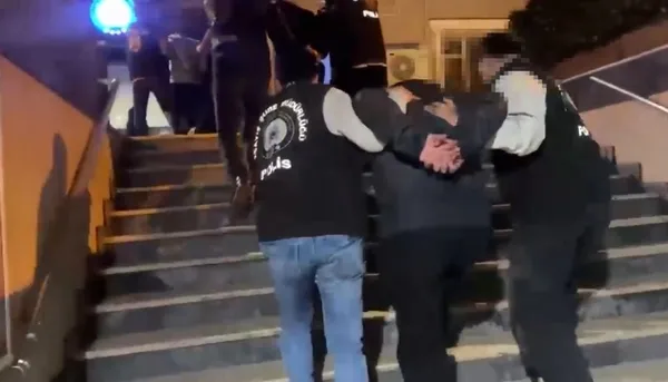A scene from the operation showing police teams escorting a suspect down the stairs.
