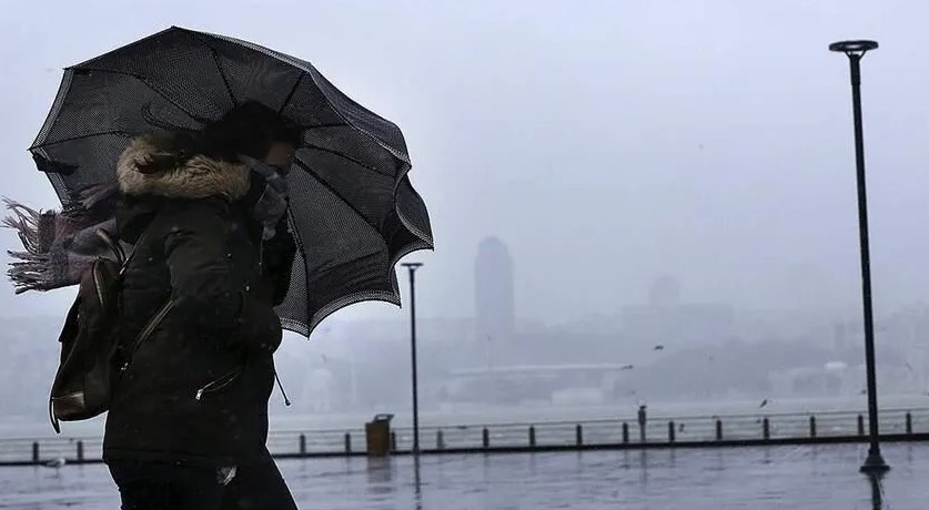 Yağışlı ve sisli havada şemsiye taşıyan bir kişi.