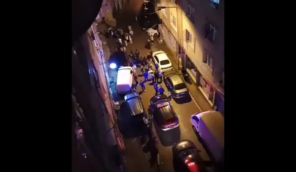 Dar bir sokakta polis ışıkları ve çevrede toplanan vatandaşların görüldüğü gece görüntüsü