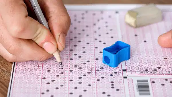 Optik sınav kağıdı üzerinde kalem, silgi ve kalemtıraş bulunan yakın plan görüntü.