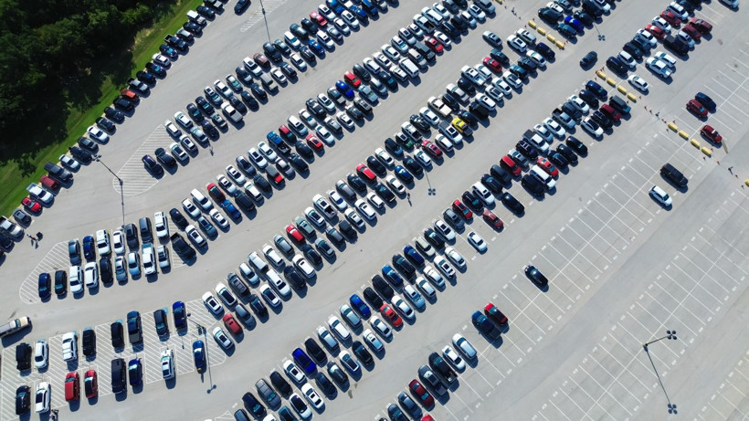 Many vehicles parked in rows in a parking lot.
