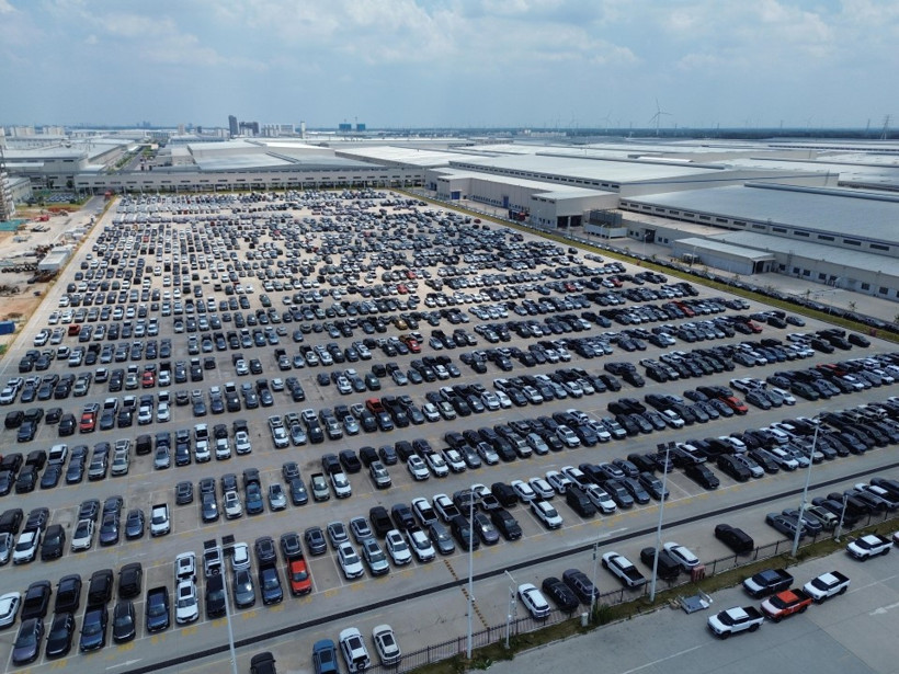Many automobiles parked in a large production or shipment area.