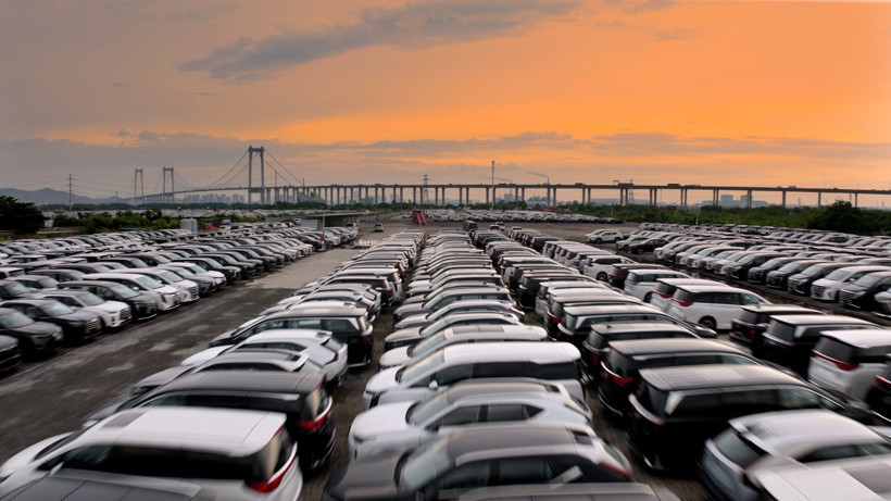 Many automobiles parked in a large area at sunset.