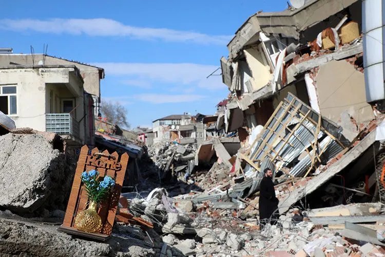 Deprem sonrası yıkılmış binaların ve enkazın görüldüğü sokak.