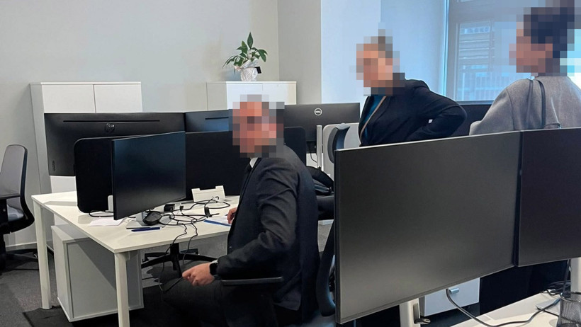 Ofis ortamında icra ve mal tespiti işlemi sırasında masalar, bilgisayar ekranları ve kişiler görülüyor.
