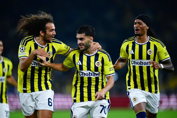 Fenerbahçeli futbolcuların sahada birlikte yürüdüğü maç fotoğrafı.