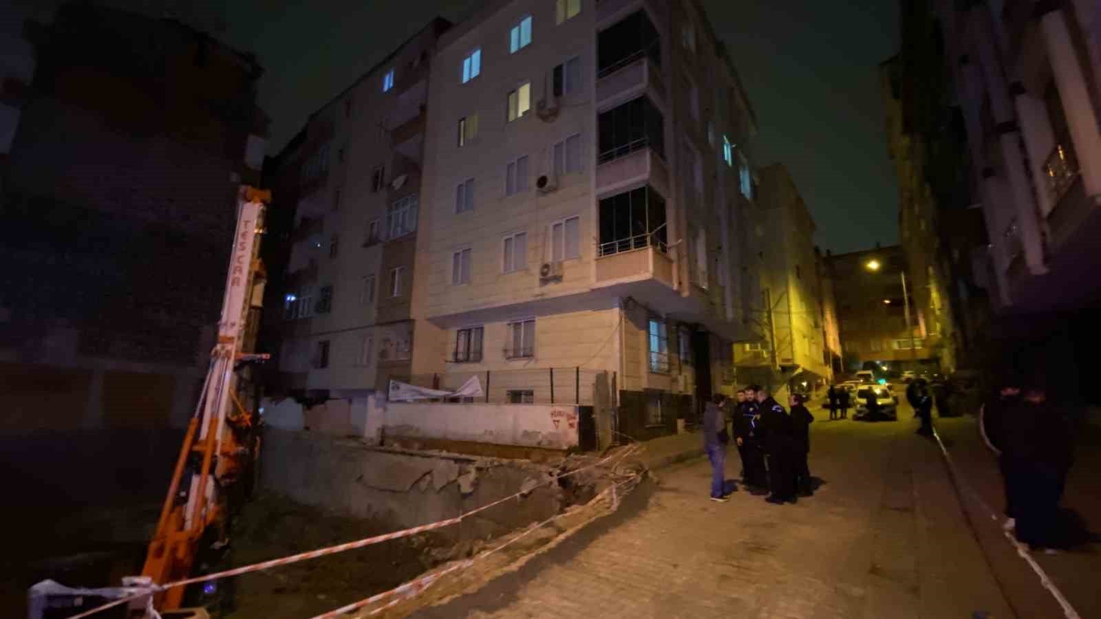 Gece çekilmiş görüntüde inşaat alanı, bitişik apartmanlar ve sokakta görev yapan ekipler.