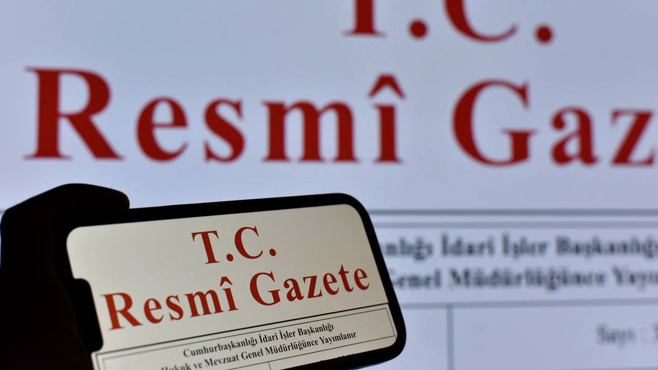 Resmi Gazete yazısının görüldüğü bir ekran ve telefon görseli.