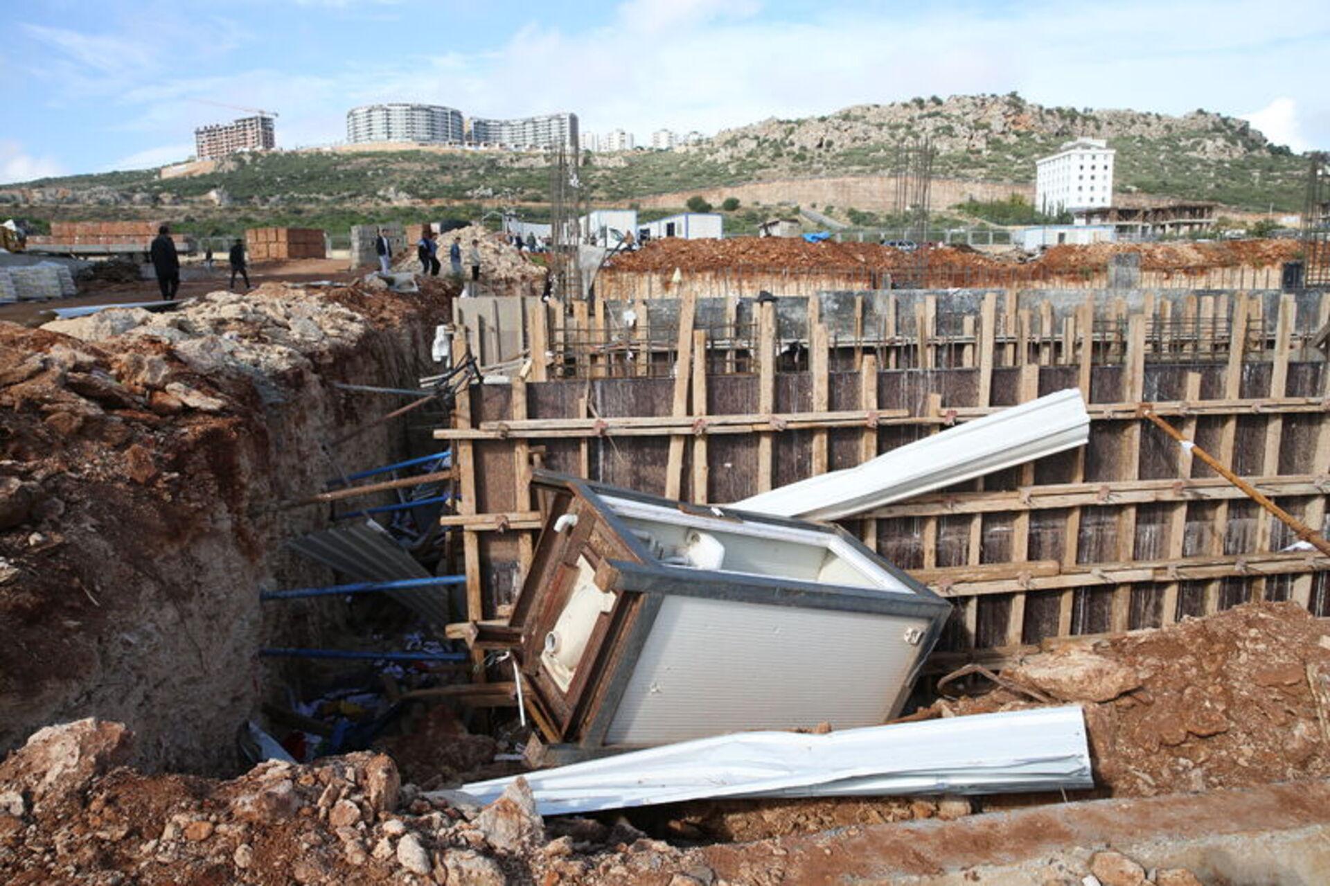 İnşaat alanında kazı bölümüne düşmüş ve hasar görmüş konteyner.