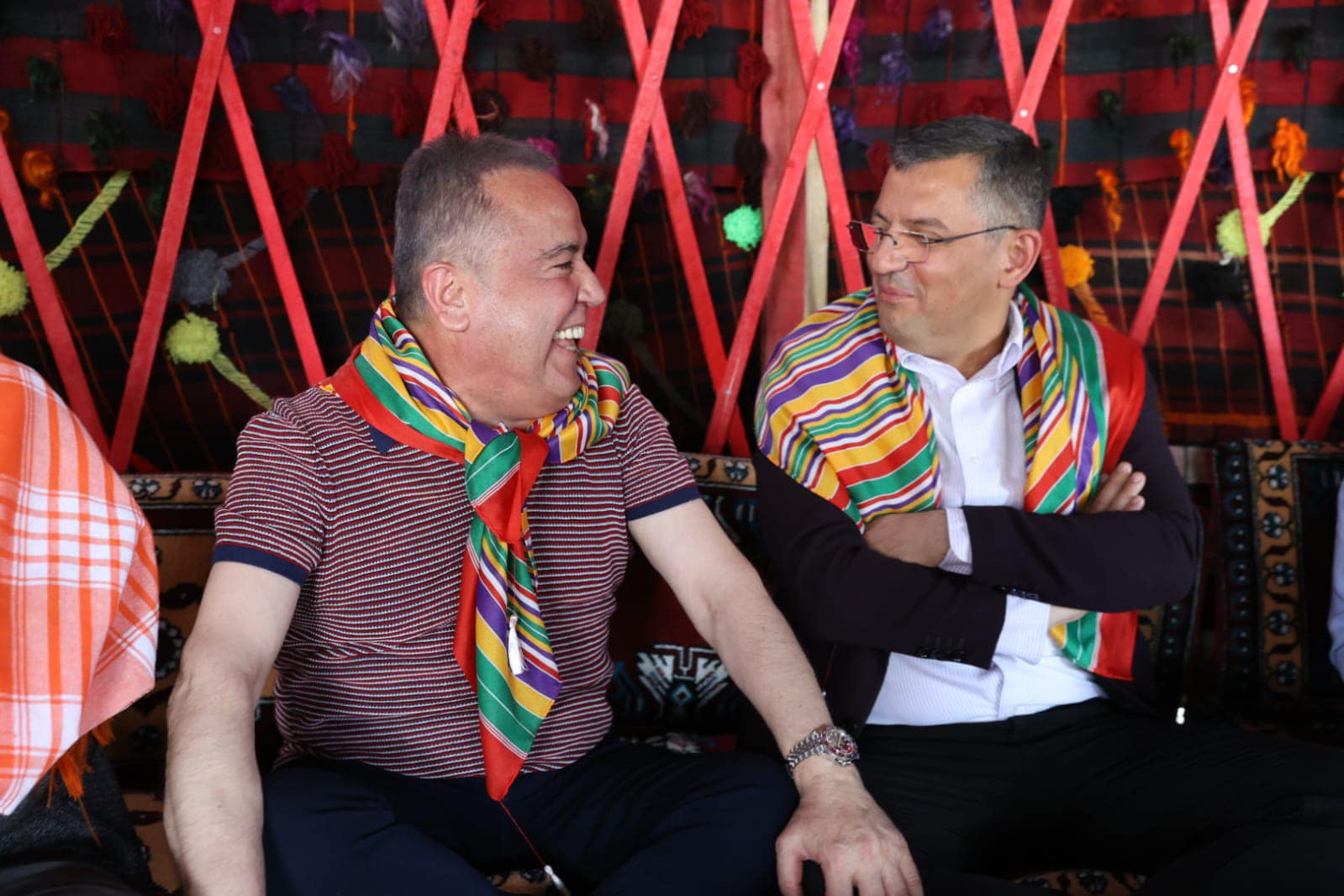 Two people are seen sitting and chatting with colorful shawls in an event area.