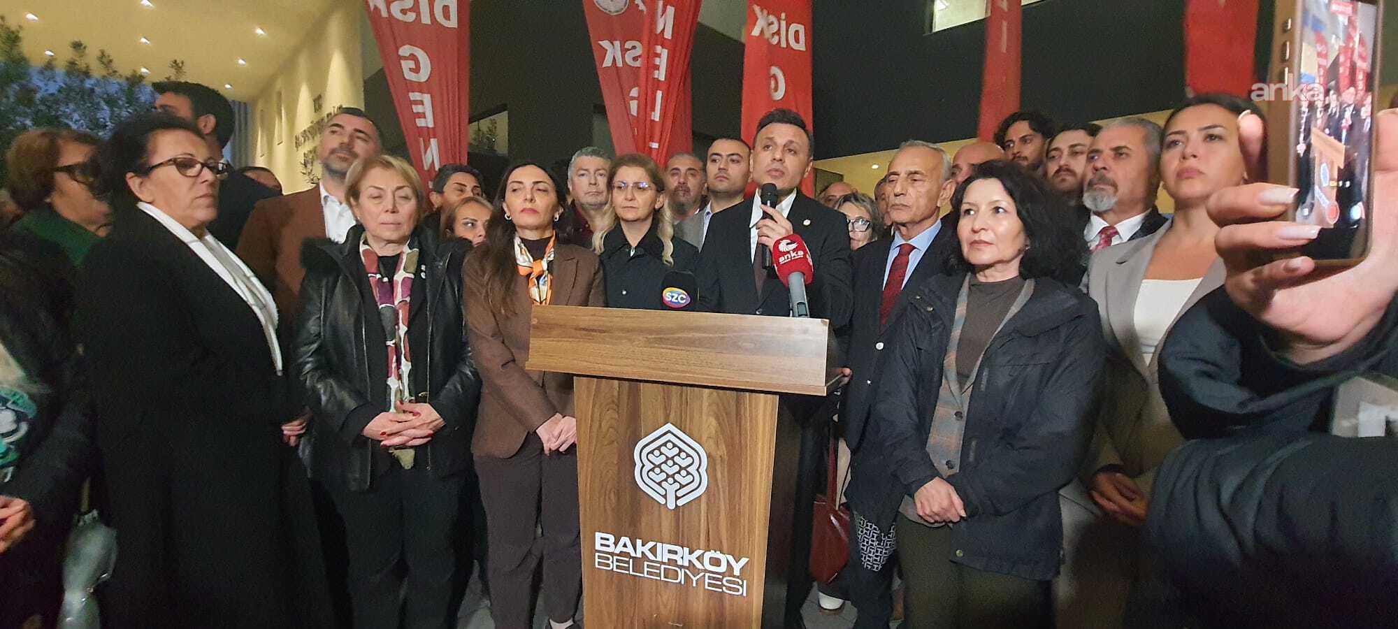 Özgür Çelik spricht vor der Stadtverwaltung Bakırköy an einem Rednerpult, umgeben von einer Menschenmenge.