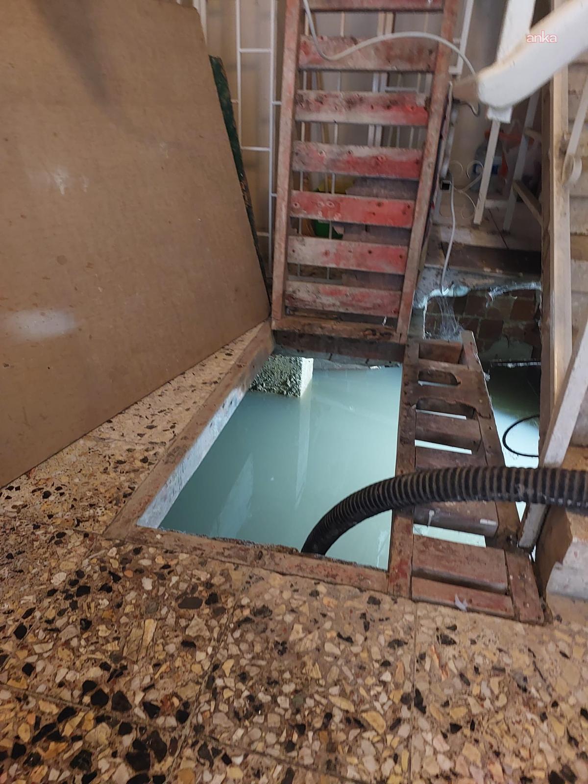 Innenraum mit wassergefüllter Bodenöffnung und Holztreppen.