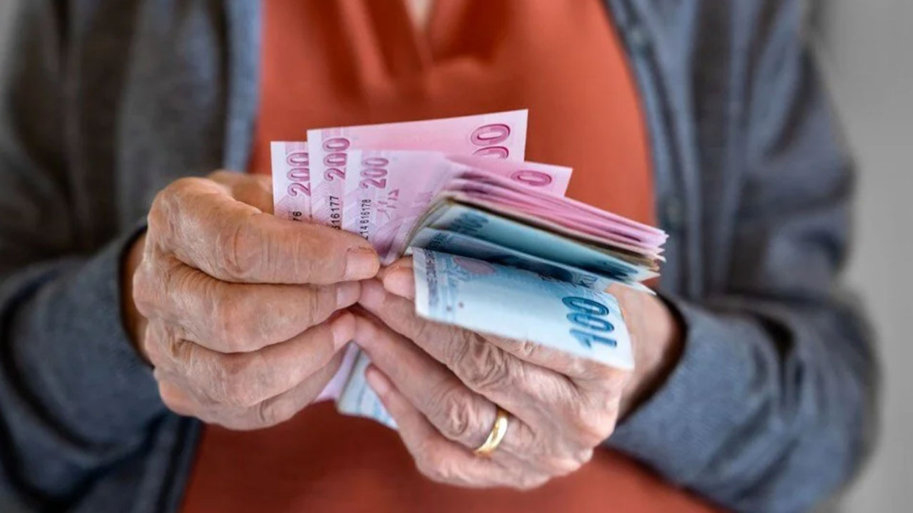 Yaşlı bir kişinin elinde Türk lirası banknotları saydığı yakın plan görsel.