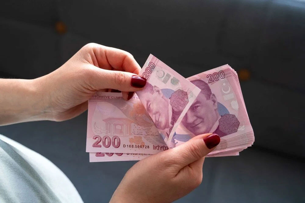 Bir kişinin elinde 200 TL banknotları tuttuğu yakın plan görsel.