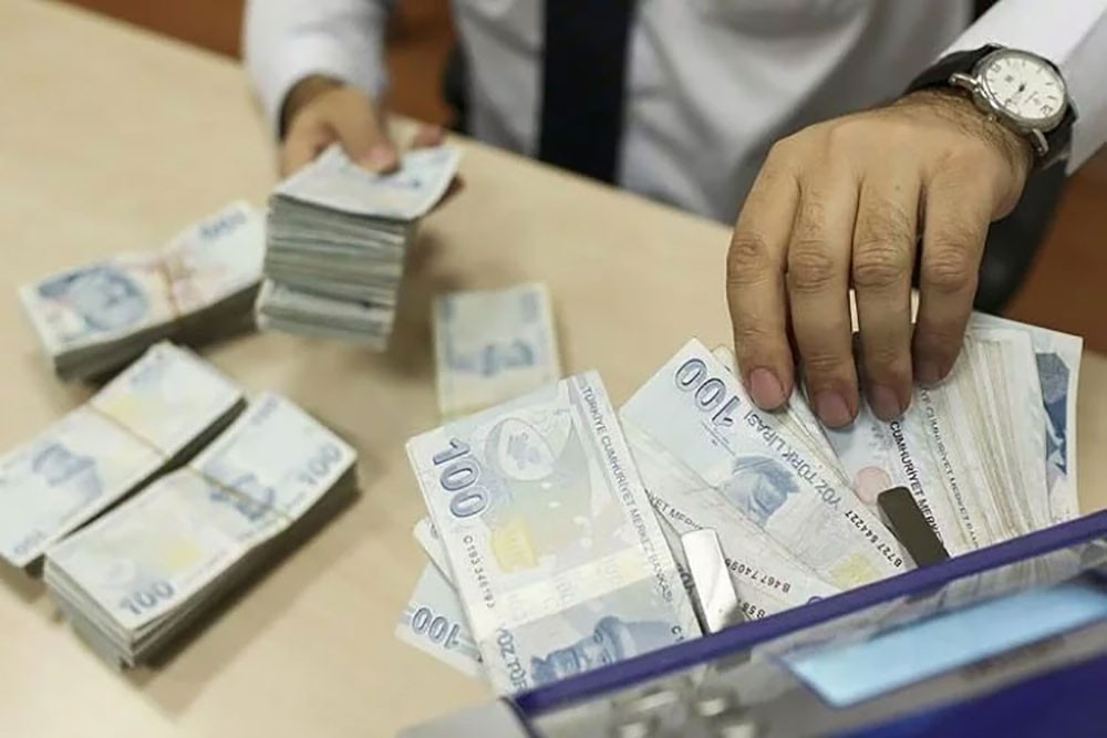 Banka gişesinde Türk lirası destelerini düzenleyen bir görevlinin elleri.