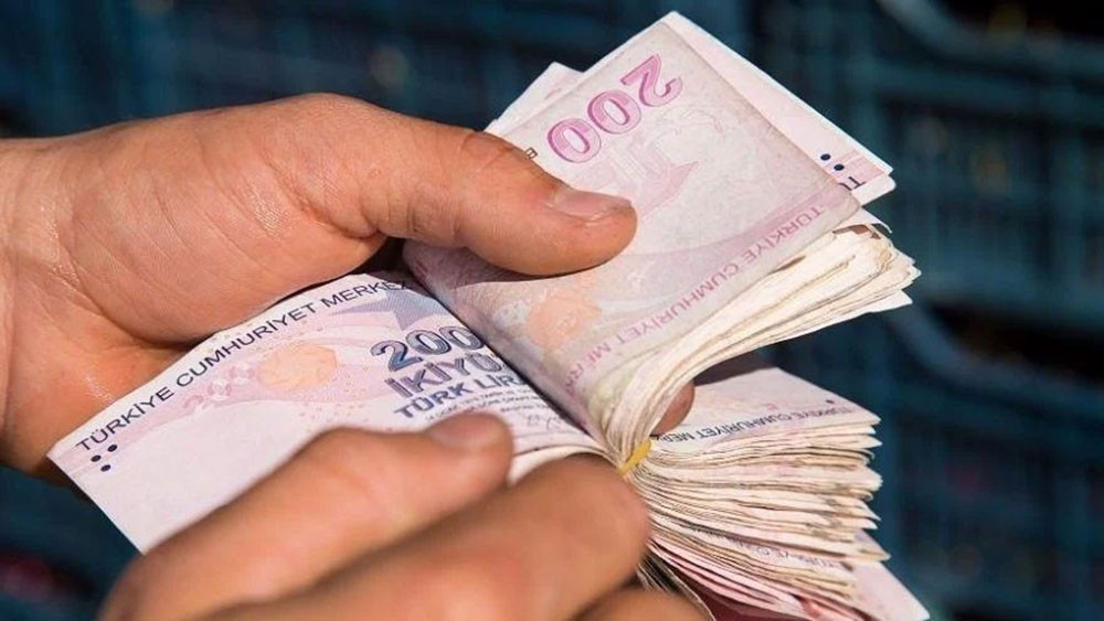 Bir kişinin 200 TL banknotlarından oluşan deste saydığı yakın plan görsel.