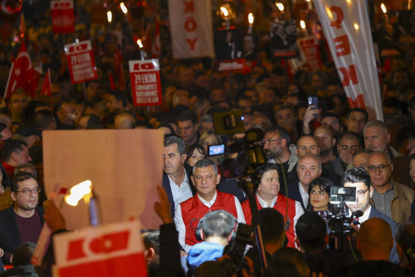 Kalabalık içinde Özgür Özel ve beraberindekilerin yürüdüğü, bayrakların taşındığı gece görüntüsü.
