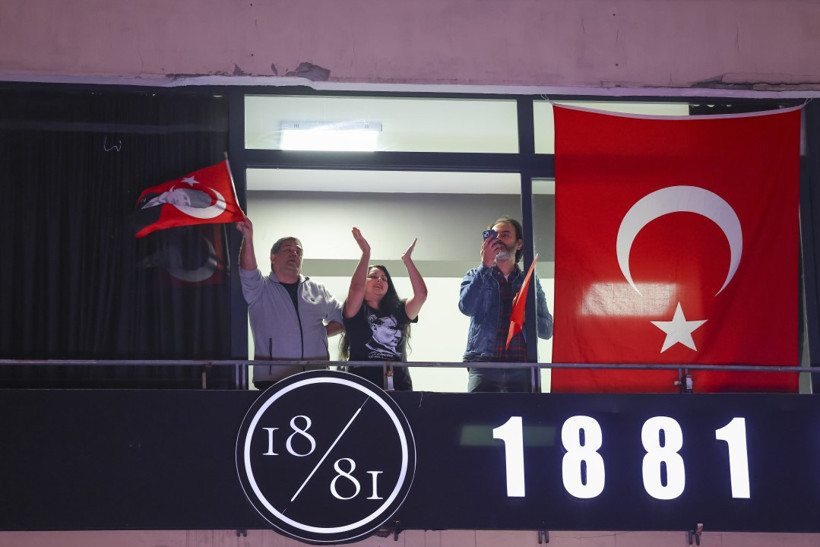 Bir balkonda Türk bayrağı asılıyken kutlamaya katılan yurttaşların görüldüğü gece fotoğrafı.
