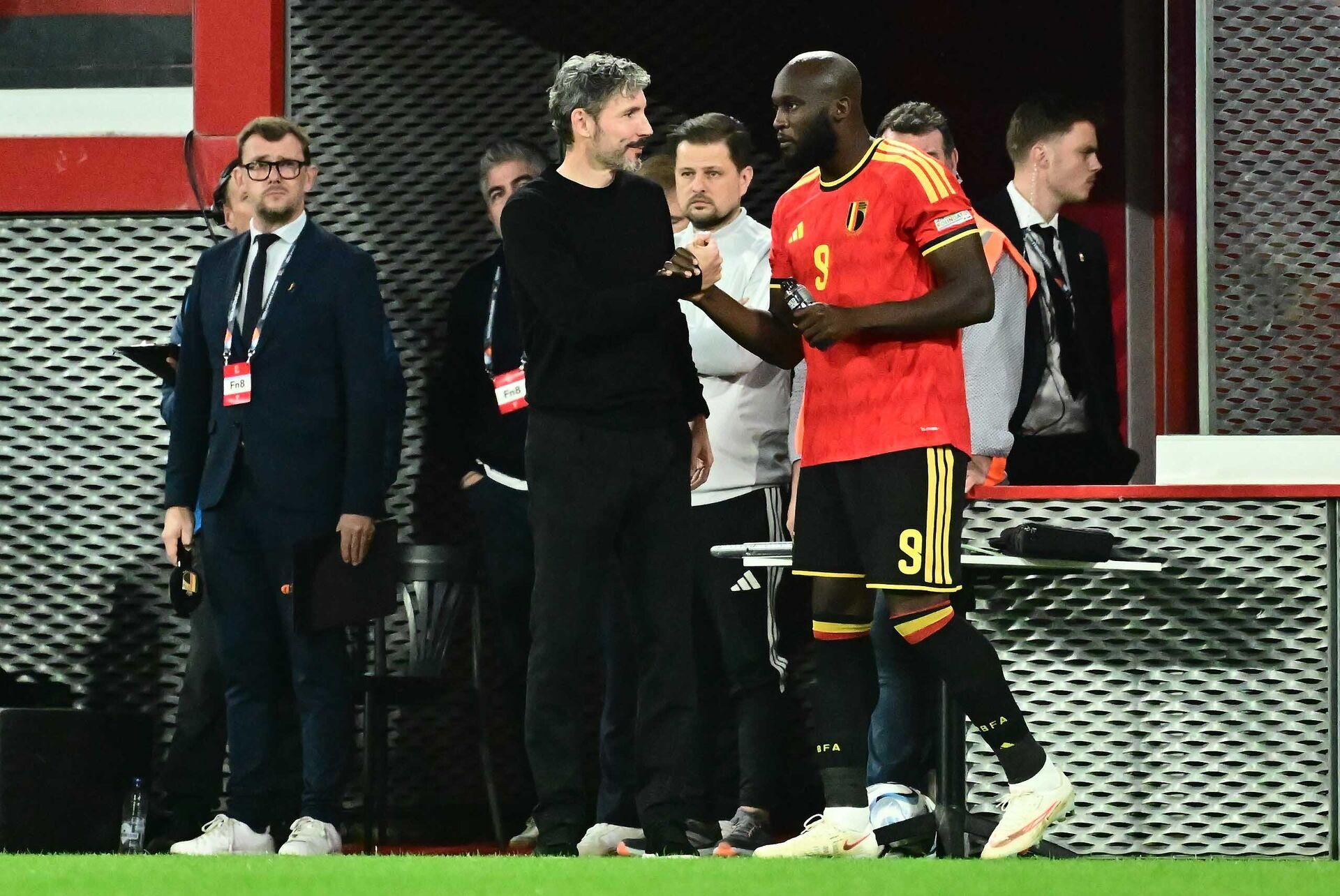 Romelu Lukaku, wearing the Belgium jersey, is seen on the sidelines with the coaching staff.