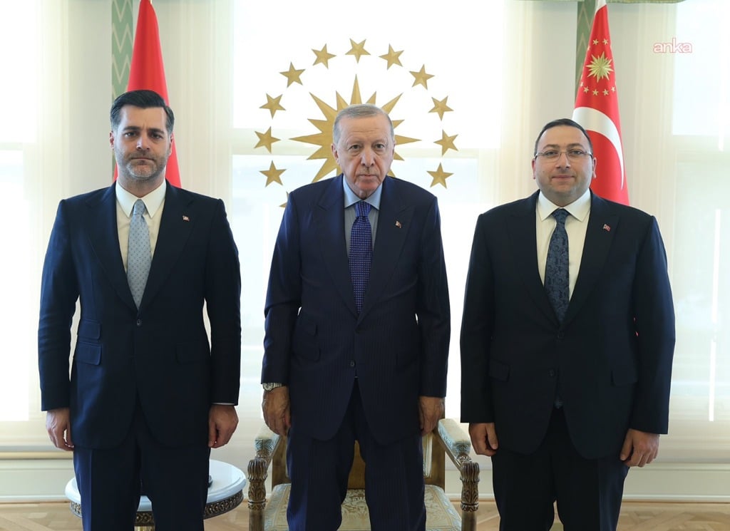 Cumhurbaşkanı Recep Tayyip Erdoğan ile iki kişinin resmi bir görüşme ortamında çekilmiş fotoğrafı.