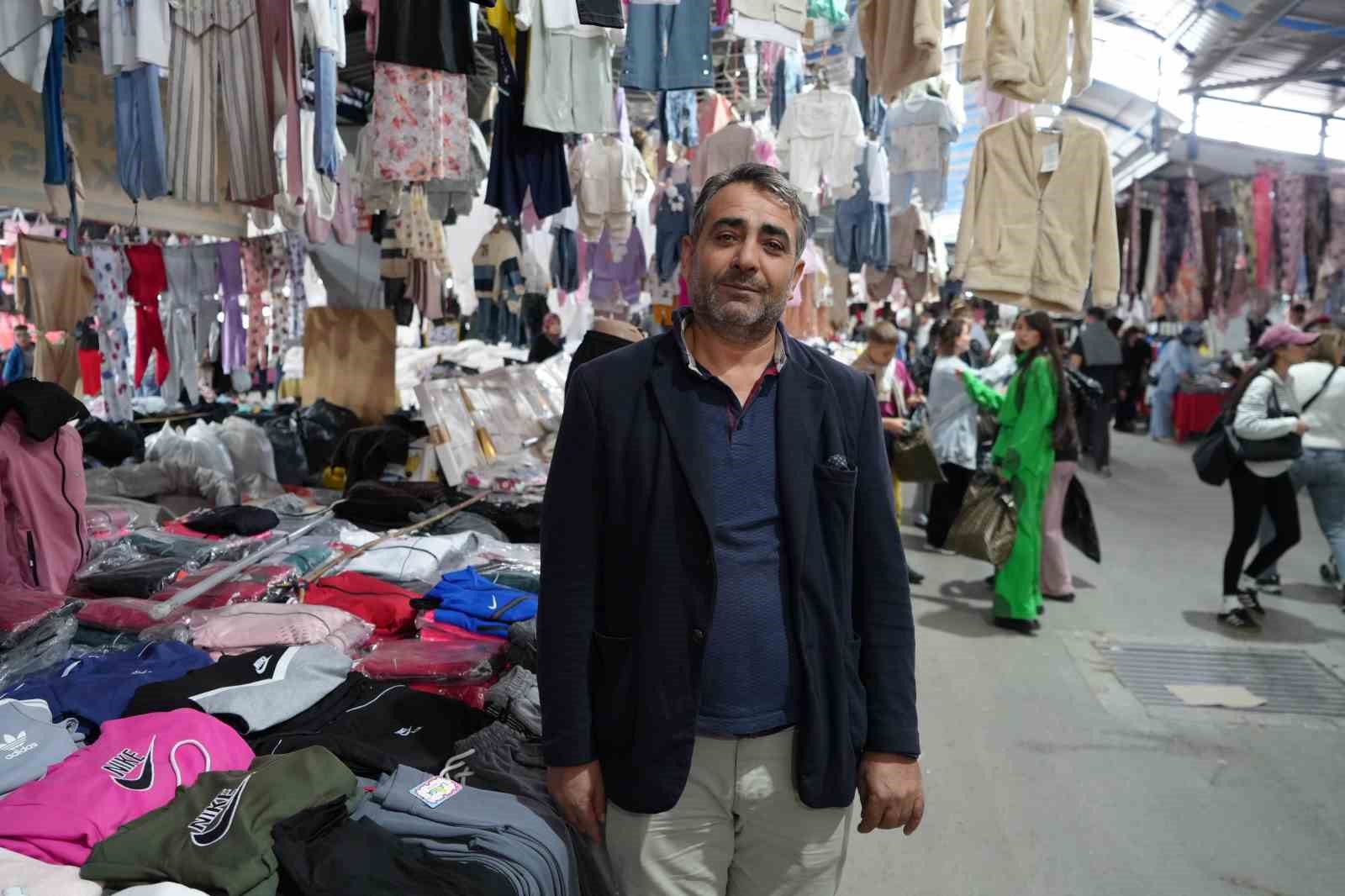 Un commerciante in un corridoio del mercato dove si trovano prodotti tessili.