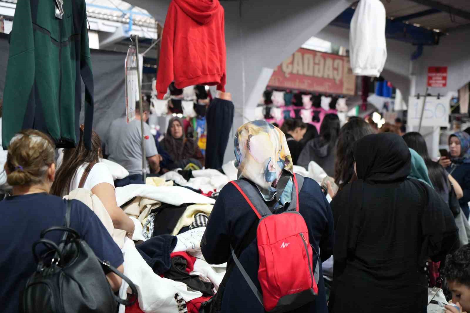 Cittadini che fanno acquisti presso un affollato banco di prodotti tessili.