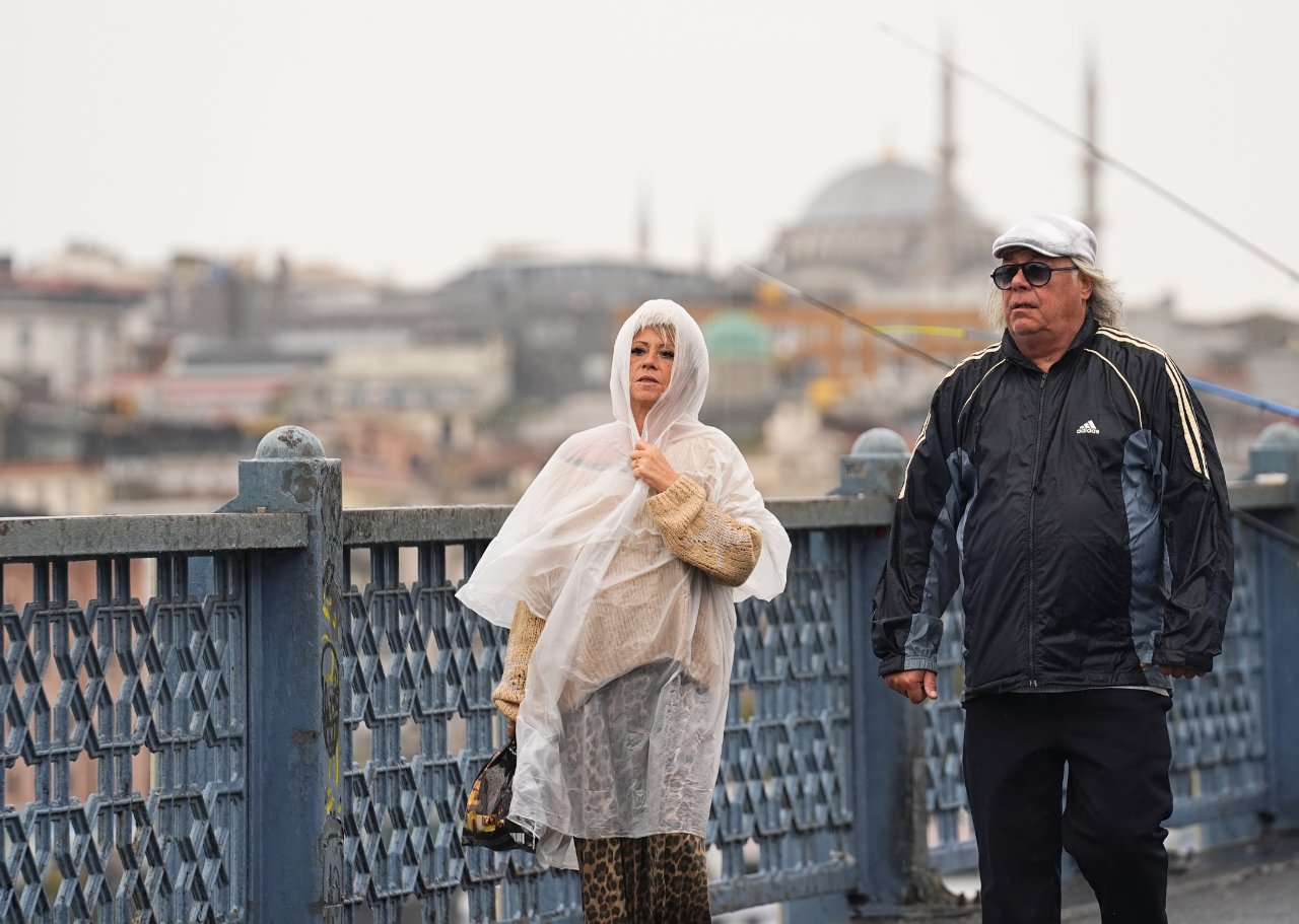 İstanbul’da yağışlı havada köprü üzerinde yürüyen kişiler.